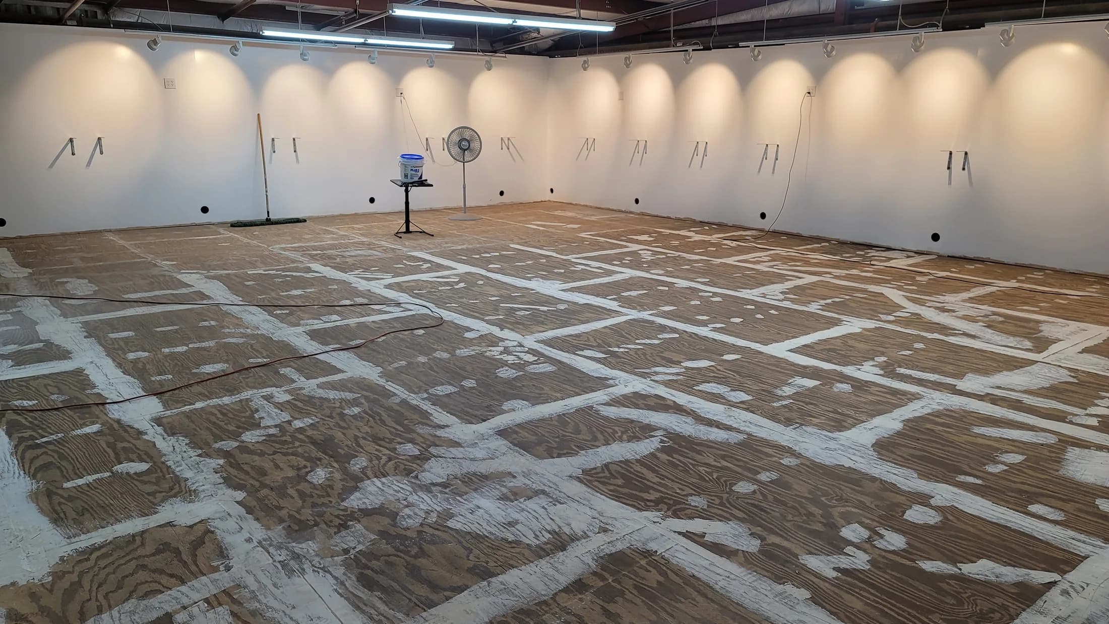 Issued lab still, 2021-01-15: empty room, wall hooks, marked plywood floor