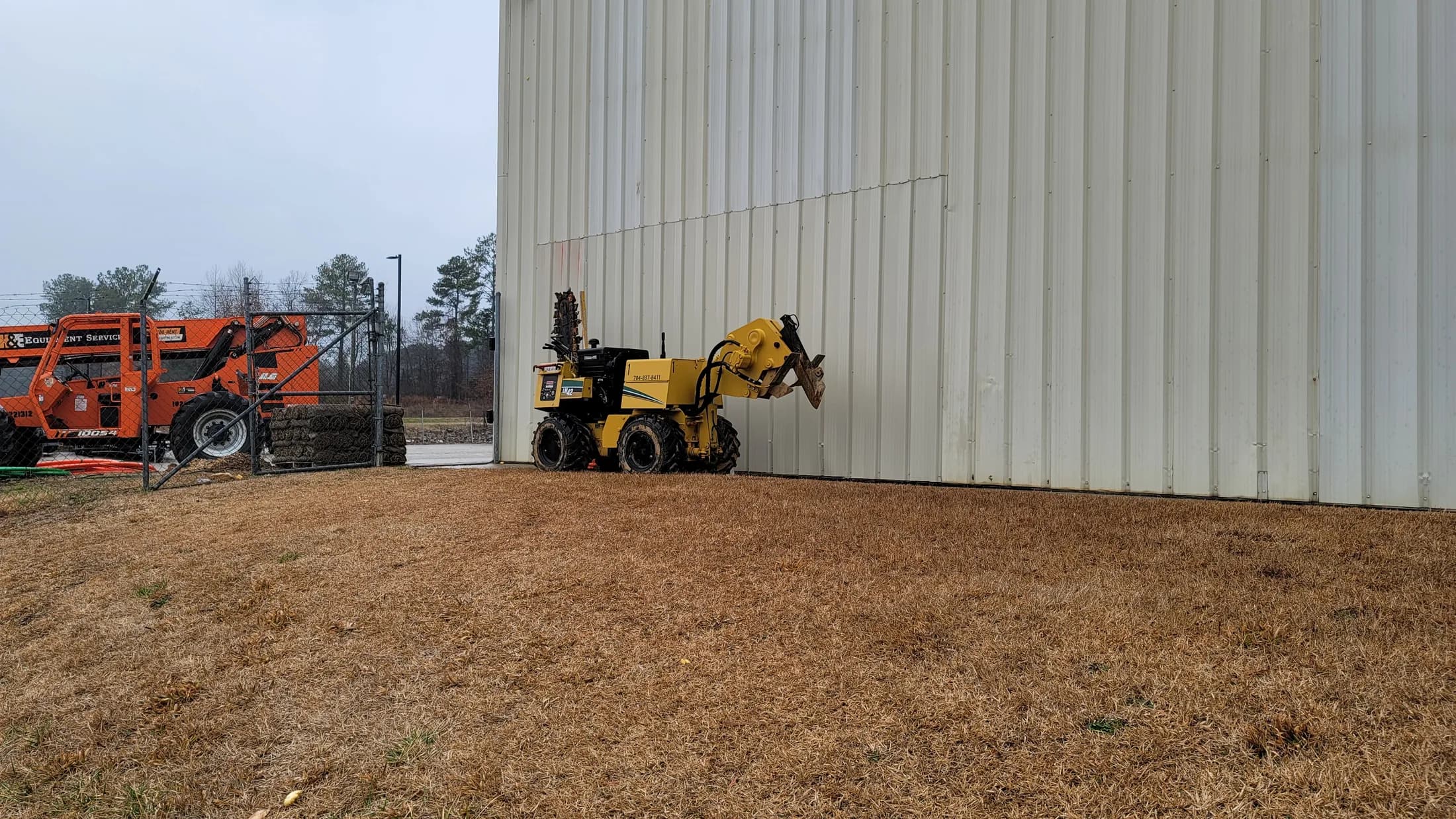 Issued lab still, 2021-02-11: lift and telehandler beside a building